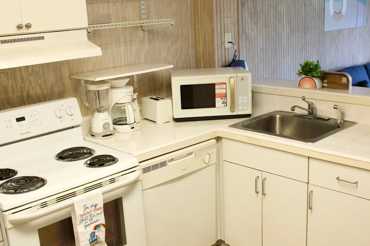 A cozy kitchenette scene focused on the stove, sink, microwave, and blender. The countertop is organized and ready for meal preparation. The space feels homey and inviting, suggesting that guests can easily prepare family recipes or quick bites.